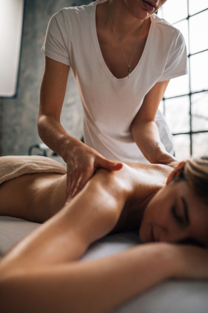 Woman receiving a relaxing shoulder massage in a tranquil spa room. Perfect for wellness and relaxation themes.